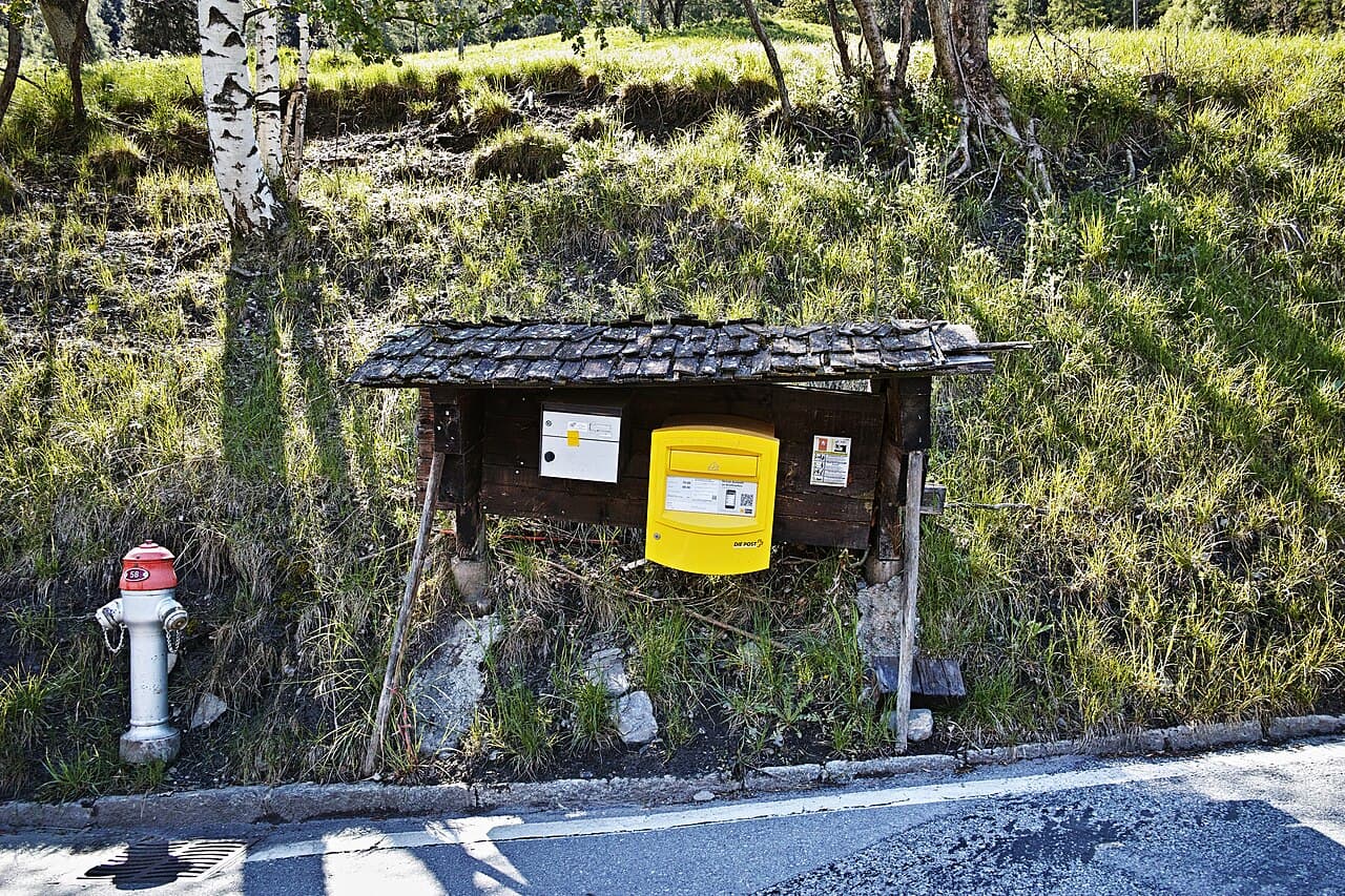 Boîte aux lettres suisse jaune le long d’une route